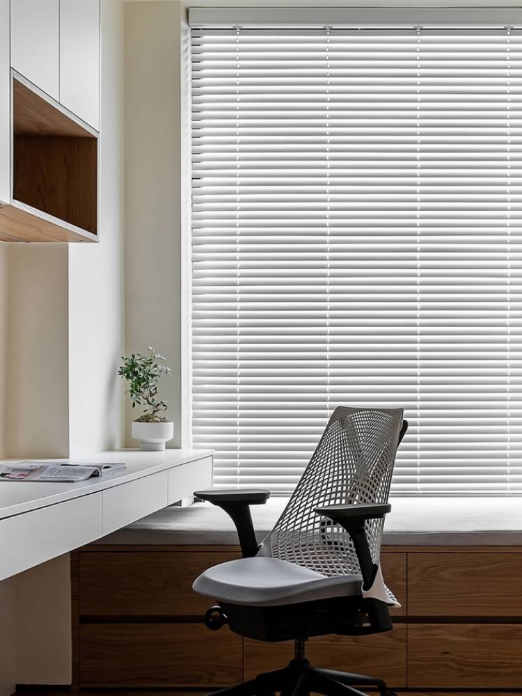 White horizontal aluminum Venetian blinds covering a home-office window