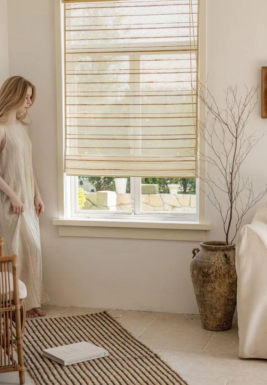 Neutral fabric Roman shade partially raised in a softly styled room